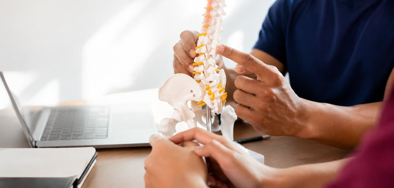 A PhysiPro Physiotherapist explaining a spine model to a patient