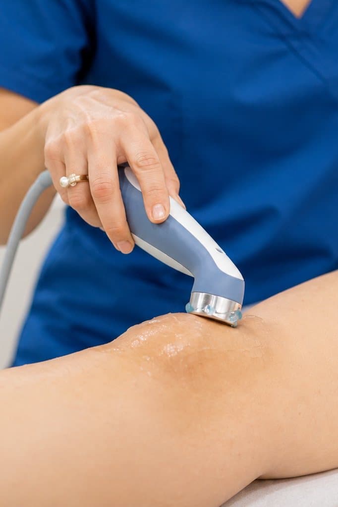 Physiotherapist applying ultrasound therapy to a patient's knee